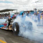 A person on a dragster with smoke coming out of the back.